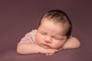 Newborn baby girl photo on pink background. Head on hands. Photo taken in Medway Kent