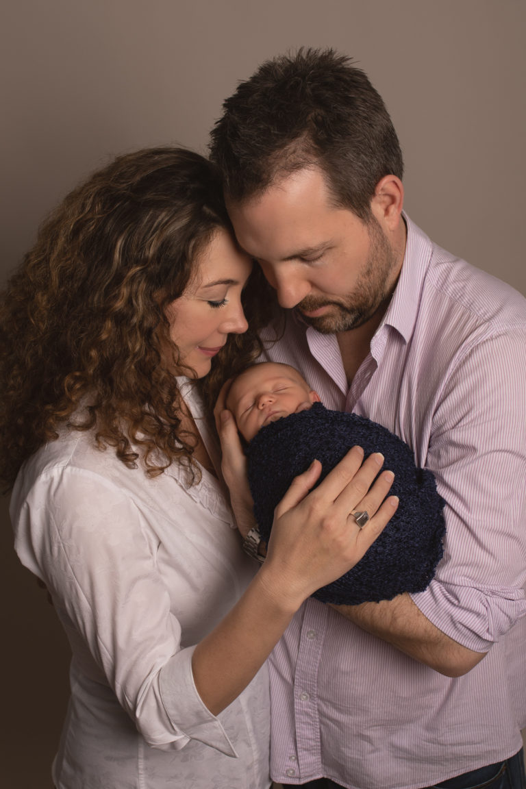 Parent photo with newborn baby boy in dads arms with mum cuddling in. Newborn photo medway