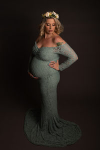 Maternity Photoshoot in Strood, Medway Kent. Pregnant lady wearing a sage green lace dress holding bump