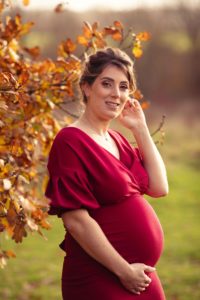 Maternity Photoshoot - mum to be holding baby bump wearing red dress in Kent 