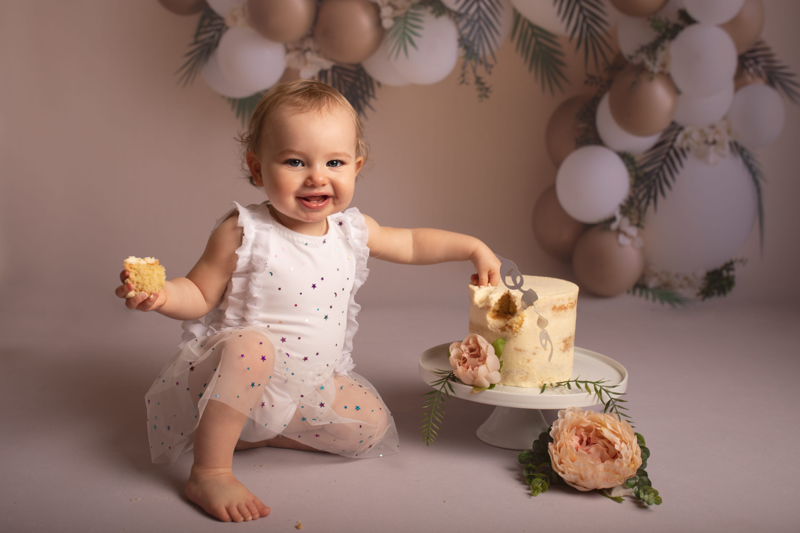 Cake Smash babies birthday girl with hand on cake and a slice in other hand by Cake Smash Photographer in Medway, Kent