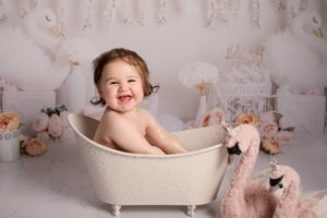 Baby Girl in bath tub after back smash. Cream bath tub with pink swans in front. Smiling One year old taken in Medway, Kent