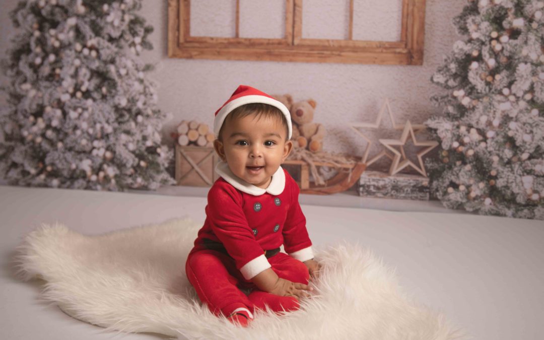 Christmas Photoshoot - 6 month old boy dressed in Santa outfit sitting on white fluffy rug with Christmas backdrop. Medway, Strood