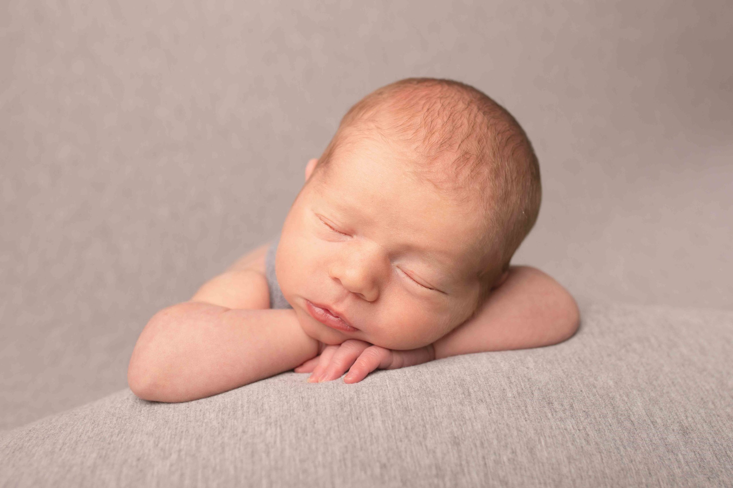 Newborn Baby Boy laying on grey blanket. Head on arms. Photographed in Medway, Kent