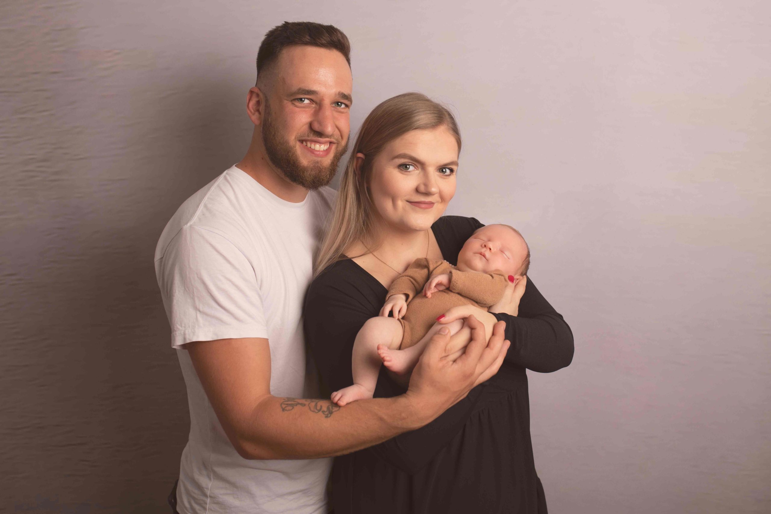 Mum is holding newborn baby girl with dad cuddling them both by Newborn Photographer Medway