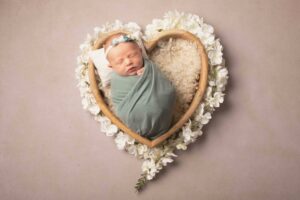 Heart shaped bowl with newborn baby wrapped in green wrap. Photographed by Newborn and Family photographer in Strood Studio Medway