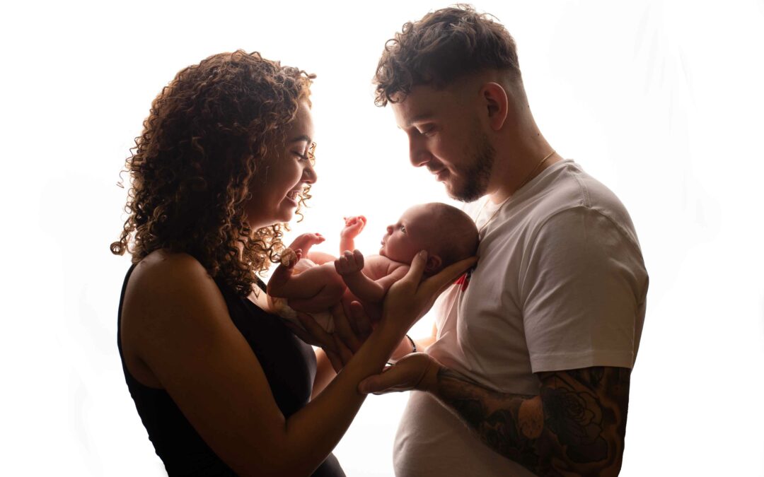 Newborn baby girl with her parents holding her. Photographed by Hannah Cornford in Medway, Kent.