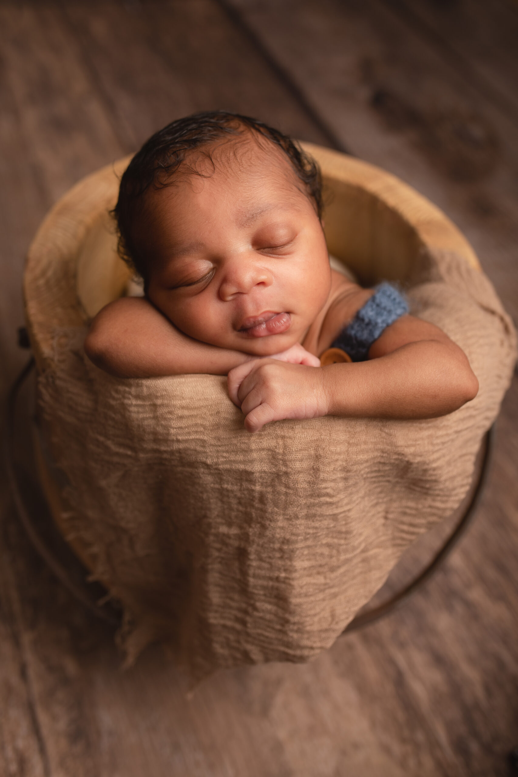 Baby boy laying on his front in honey wooden bucket. Photographed in Medway Kent by Hannah Cornford Photography